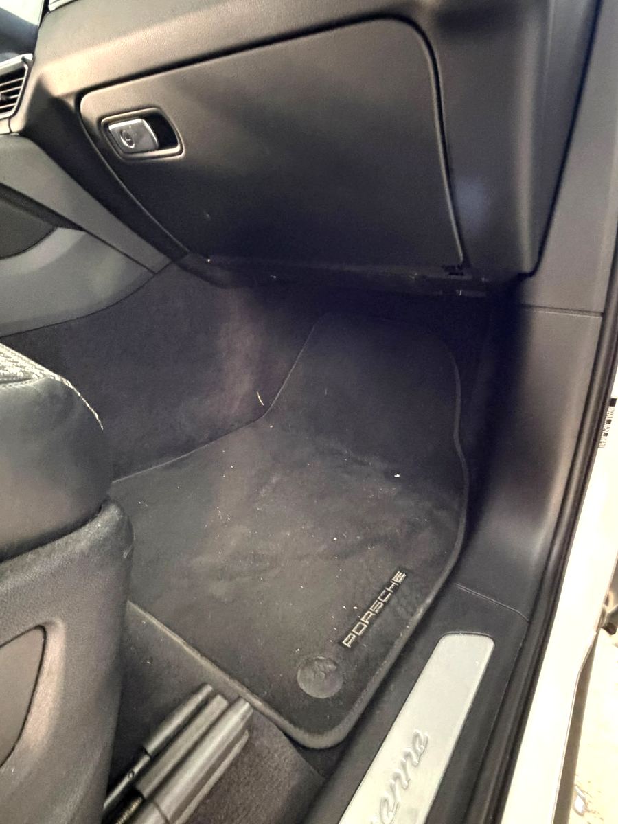 Fußraum eines Porsche Cayenne mit Staub und Schmutz auf der Matte